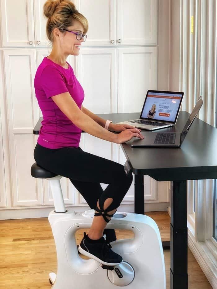 woman sitting at desk bike and working